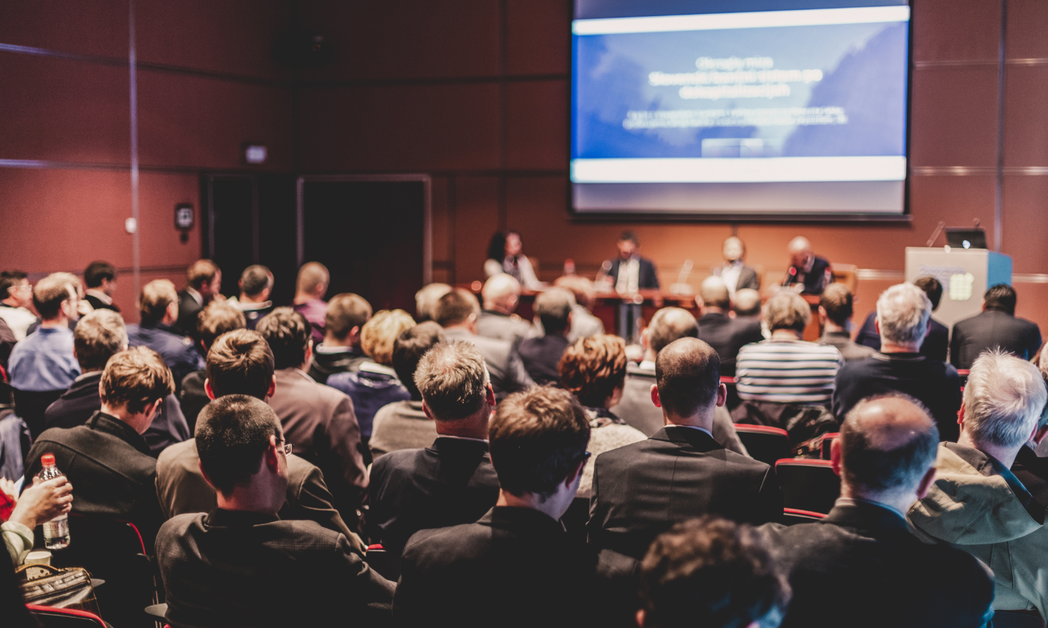 A group of people seated at a business conference-type event.